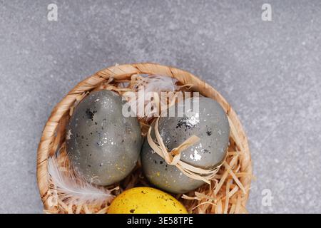 Décoration rustique d'oeufs de Pâques dans le nid sur fond gris Banque D'Images