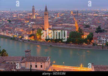 Vue panoramique de Vérone avec le fleuve Adige, églises historiques et rues illuminées au crépuscule, Italie. Banque D'Images