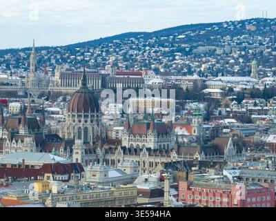 Bâtiment du Parlement, église Matthias, bastion des pêcheurs, collines de Buda enneigées derrière, ciel couvert Banque D'Images