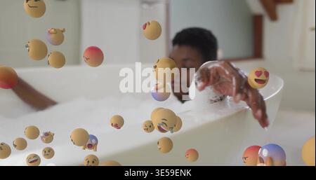 Femme couchée se baignant dans une baignoire blanche dans la salle de bain avec mousse, sphères emoji, fenêtre, poutre de plafond Banque D'Images