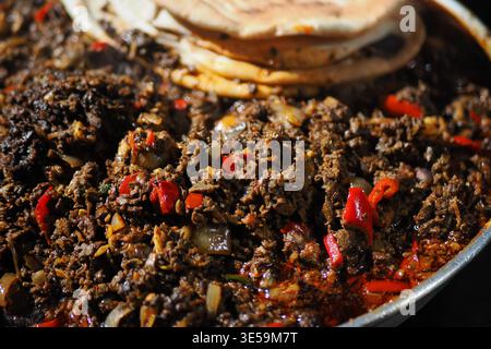 Cuisson du ragoût de bœuf avec des pains plats dans une poêle Banque D'Images