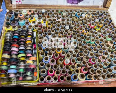 grande collection de bobines de fil à coudre colorées soigneusement disposées dans des accessoires de confection de boîte Banque D'Images