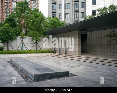 Cette cour urbaine pavée moderne présente un plan d'eau rectangulaire, des murs en pierre sombre et des sculptures en bronze à la lumière du jour. La scène représente conte Banque D'Images