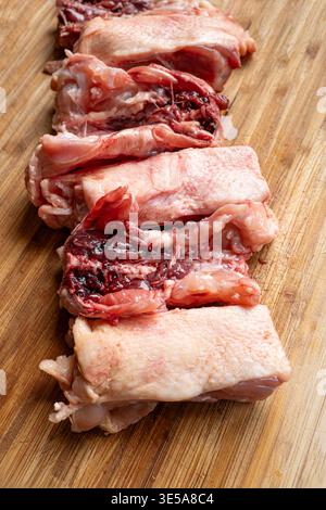Une rangée de dos de poulet frais et crus coupés en morceaux sur une planche à découper en bois. Gros plan, pas de gens Banque D'Images