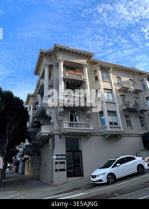 Bâtiment historique de plusieurs étages avec des détails architecturaux ornés, des balcons et un panneau de rue à sens unique, situé dans un cadre urbain sous un ciel bleu Banque D'Images