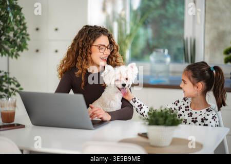 Mère, fille et chien travaillant et jouant ensemble Banque D'Images