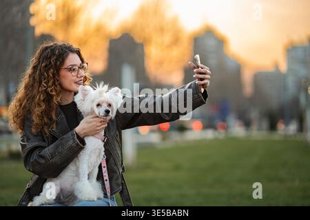 Femme et chien prenant un selfie à l'extérieur pendant le coucher du soleil Banque D'Images