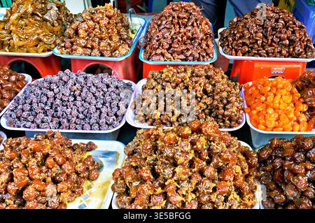 Les vendeurs vendent divers types de fruits secs et de collations sur un marché à Hanoi, au Vietnam pendant la journée. Beaucoup de gens s'arrêtent pour regarder et acheter. Banque D'Images
