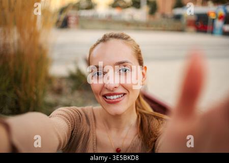 Jeune femme souriante prenant selfie dans la rue de Vienne Banque D'Images