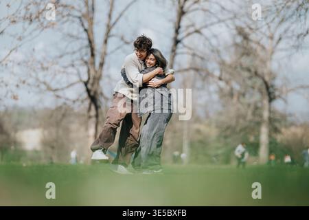 Deux amis se serrant dans les bras et riant ensemble dans un parc par un après-midi de printemps ensoleillé Banque D'Images