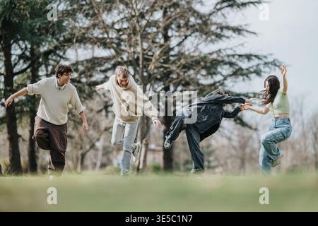 Quatre amis riant et courant ensemble dans un parc par une journée ensoleillée Banque D'Images