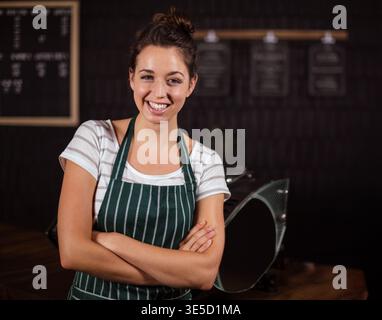 Barista femme qui utilise une machine à espresso derrière le comptoir du café avec des tableaux de menu au tableau noir. Café, artisan, minimaliste, hospitalité, hospitalité dans Banque D'Images