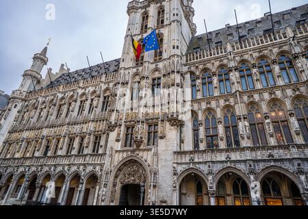Vue rapprochée et inclinée de la façade de l'hôtel de ville de Bruxelles. L'image met en évidence les sculptures gothiques complexes, les fenêtres pointues, et le belge et E. Banque D'Images