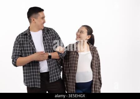 Jeune couple en chemises à carreaux marchant ensemble en studio Banque D'Images