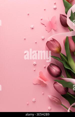Élégant plat printanier avec tulipes roses et violettes avec un ruban fluide, accentué par des papillons en papier, des perles et des décorations en forme d'étoile sur Banque D'Images
