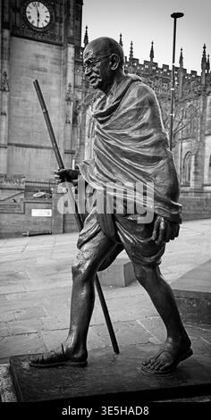 Statue du Mahatma Gandhi devant la cathédrale de Manchester sur Victoria Street, Manchester, avec l'architecture de la cathédrale derrière dans une scène de ville monochrome Banque D'Images