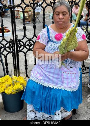 Une femme maya tisse des frondes de palmier dans une décoration traditionnelle à l'extérieur de la cathédrale de Mérida le dimanche des Rameaux à Mérida, Yucatán, Mexique Banque D'Images