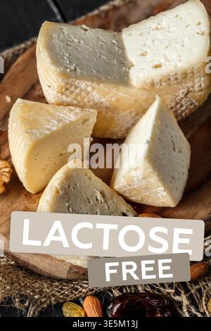 Dégustez du fromage sans lactose sur une planche de bois avec des noix et des fruits secs Banque D'Images