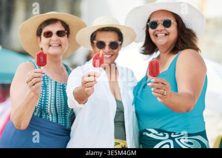 Sourire, voyage et popsicle avec les vieilles femmes à la plage pour les vacances d'été, la retraite et le voyage. Week-end, aventure tropicale et crème glacée avec Banque D'Images