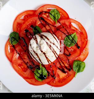 Fromage Burrata avec tomates fraîches et glaçage balsamique en gros plan. Vue de dessus. Texture Banque D'Images