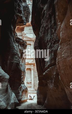 Le Trésor à Petra vu à travers le canyon Siq avec cavalier de chameau sur le chemin sablonneux en Jordanie Banque D'Images