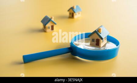 Loupe se concentrant sur un petit modèle de maison pour la recherche de propriétés et l'analyse du marché immobilier. Banque D'Images
