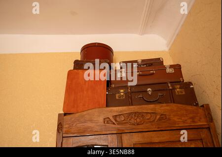 Valises vintage et une boîte à chapeau ronde empilées sur le dessus d'une armoire en bois. Bagage détaillé. Concept de voyage historique, souvenirs nostalgiques, et Banque D'Images