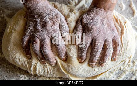 Mains féminines fabriquant de la pâte pour pizza. Pâtes les mains des femmes. Faire de la pâte par des mains masculines à la boulangerie. Concept alimentaire. Pâte à main Banque D'Images