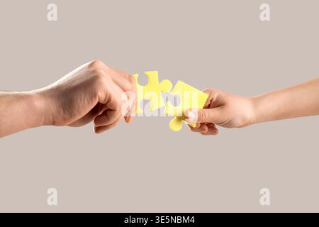 Fermez les mains tenant en essayant de connecter deux pièces de puzzle. Casse-tête reliant les mains. Solution des problèmes. Les mains des hommes et des enfants se connectent Banque D'Images