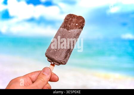 Barre de crème glacée au chocolat sur un bâton avec fond de plage tropicale Banque D'Images
