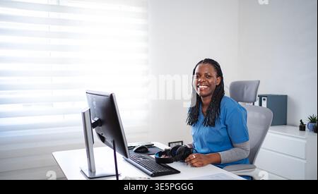 Professionnelle de santé afro-américaine souriante lors d'une consultation de télésanté Banque D'Images