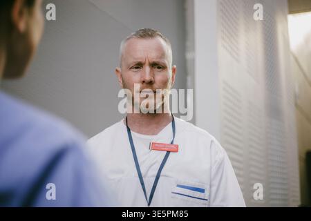 Expert médical masculin confus debout avec collègue féminine dans le hall de l'hôpital Banque D'Images