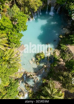 Chutes de Cambugahay, Siquijor, Philippines – 14 avril 2025 : vue aérienne d’un visiteur nageant dans des piscines turquoises sous des cascades. Banque D'Images