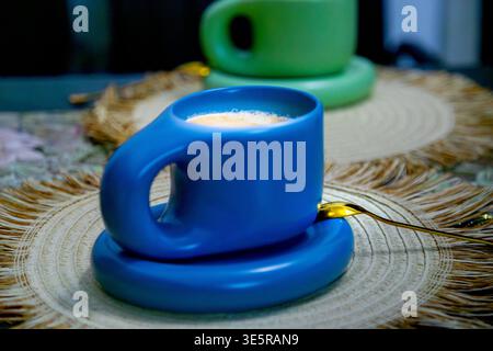 Café du matin servi dans une tasse de designer moderne avec une deuxième tasse floue en arrière-plan, scène de nature morte confortable Banque D'Images