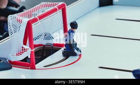 Gros plan d'un gardien de but bleu dans un match de hockey sur table défendant le but. Banque D'Images