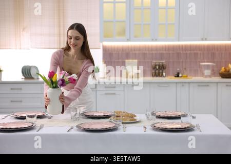 Femme souriante mettant la table pour le dîner dans la cuisine. Espace pour le texte Banque D'Images