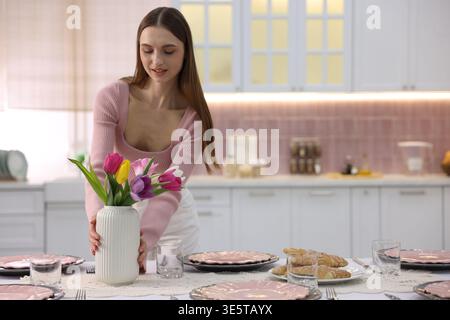 Femme souriante mettant la table pour le dîner dans la cuisine. Espace pour le texte Banque D'Images