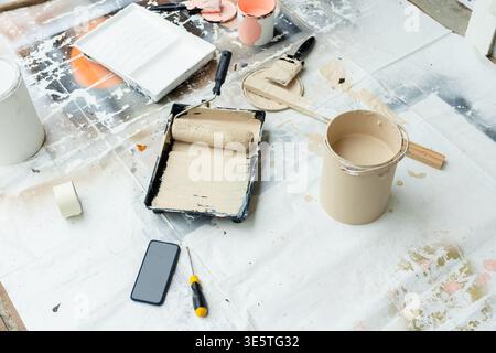 Zone de peinture sur la toile de chute montrant le rouleau dans le plateau avec boîte beige, brosse, tournevis de téléphone à ruban Banque D'Images