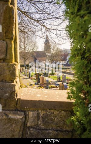 Vue à travers une fenêtre d'un cimetière et d'une église dans un village historique, Gechingen, district de Calw, Allemagne Banque D'Images