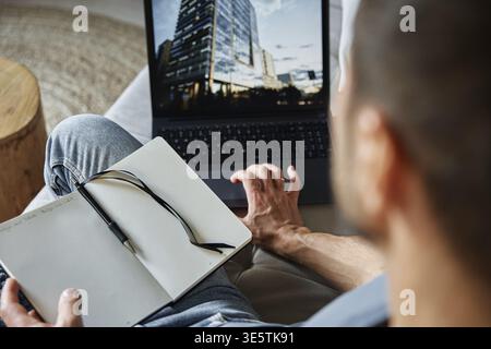 Homme assis sur un canapé et utilisant un ordinateur portable. Travailleur indépendant travaillant à domicile. Travail à distance et travail à domicile Banque D'Images
