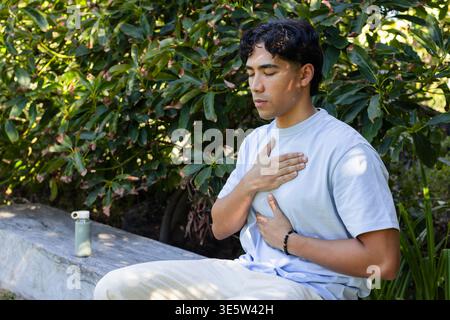 Homme asiatique 20s assis sur un banc en béton dans le jardin pratiquant la respiration avec bracelet perlé Banque D'Images