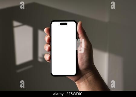 Main tenant une maquette de smartphone avec un écran vierge en affichage mobile vertical, un modèle propre pour l'illustration de marque, la présentation d'application et le numérique Banque D'Images