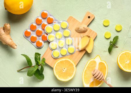Gouttes de toux dans des cloques avec des citrons, des feuilles de menthe et de la racine de gingembre sur fond vert Banque D'Images