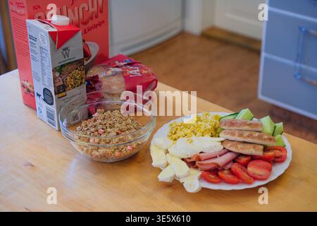 Jakkvik, Suède - 28 juillet 2024 : un copieux petit déjeuner incluant du lait de céréales ICA Crunchy et une assiette variée de protéines et de légumes dans un Swedis Banque D'Images