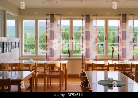 Jakkvik, Suède - 28 juillet 2024 : la salle à manger vide de l'auberge STF Jakkvik Fjallstation montrant un design intérieur en bois et des rideaux colorés sur un br Banque D'Images