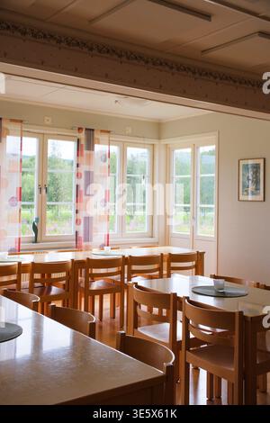 Jakkvik, Suède - 28 juillet 2024 : la salle à manger vide de l'auberge STF Jakkvik Fjallstation montrant un design intérieur en bois et des rideaux colorés sur un br Banque D'Images