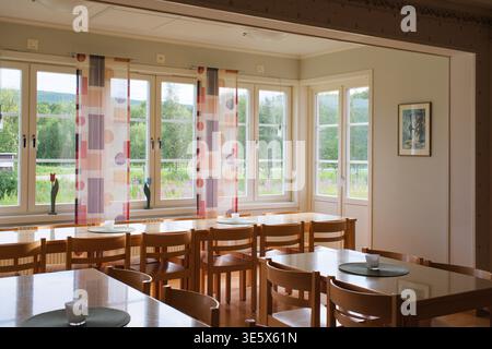 Jakkvik, Suède - 28 juillet 2024 : la salle à manger vide de l'auberge STF Jakkvik Fjallstation montrant un design intérieur en bois et des rideaux colorés sur un br Banque D'Images