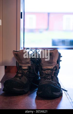 Jakkvik, Suède - 28 juillet 2024 : une paire de chaussures de randonnée bien utilisées reposant près d'une fenêtre à l'intérieur de l'hébergement STF Jakkvik lors d'un trek d'été sur t Banque D'Images