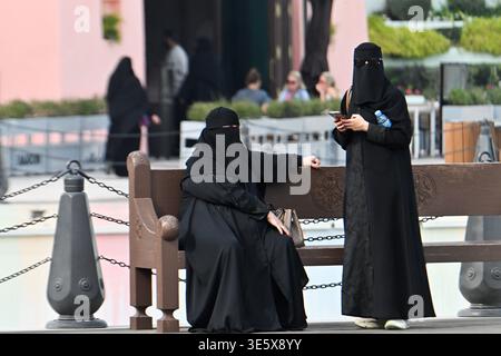 Qatar, Doha deux femmes portant des tchadors noirs et des niqabs sur un banc dans le district de Mina Banque D'Images