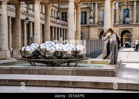 Touristes photographiant Fontaines de Pol Bury 'Spherades' (1985), fontaines cinétiques en acier inoxydable dans la Cour d'Orléans, Palais Royal, à Paris, France. Banque D'Images